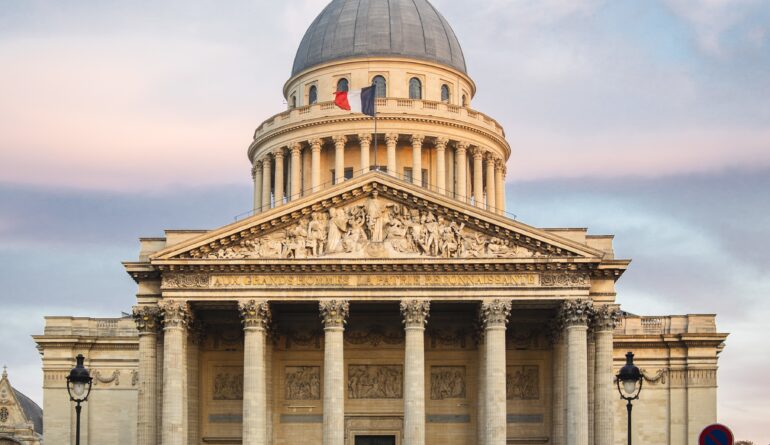 Pantheon surrounded by people under a cloudy sky during sunset in Paris in France